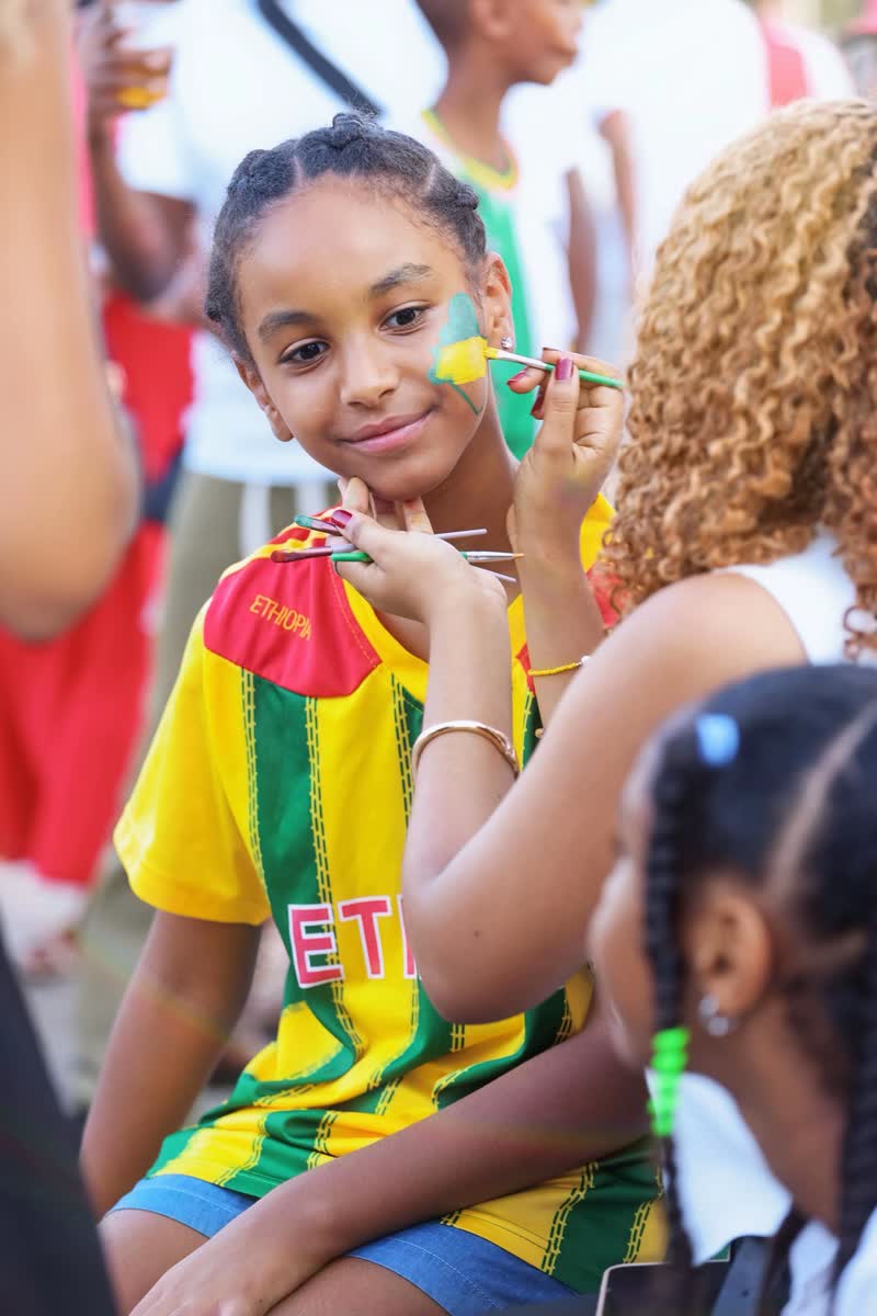 A young girl in an Ethiopia shirt having the Ethiopian flag painted on her cheek